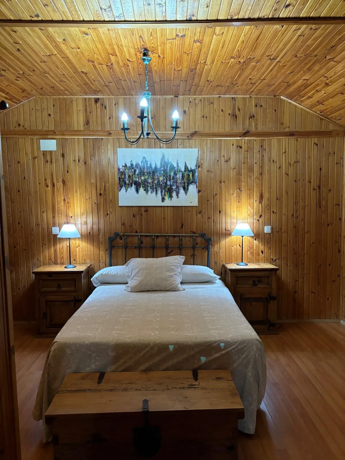 Cama de matrimonio en bungalow con paredes de madera