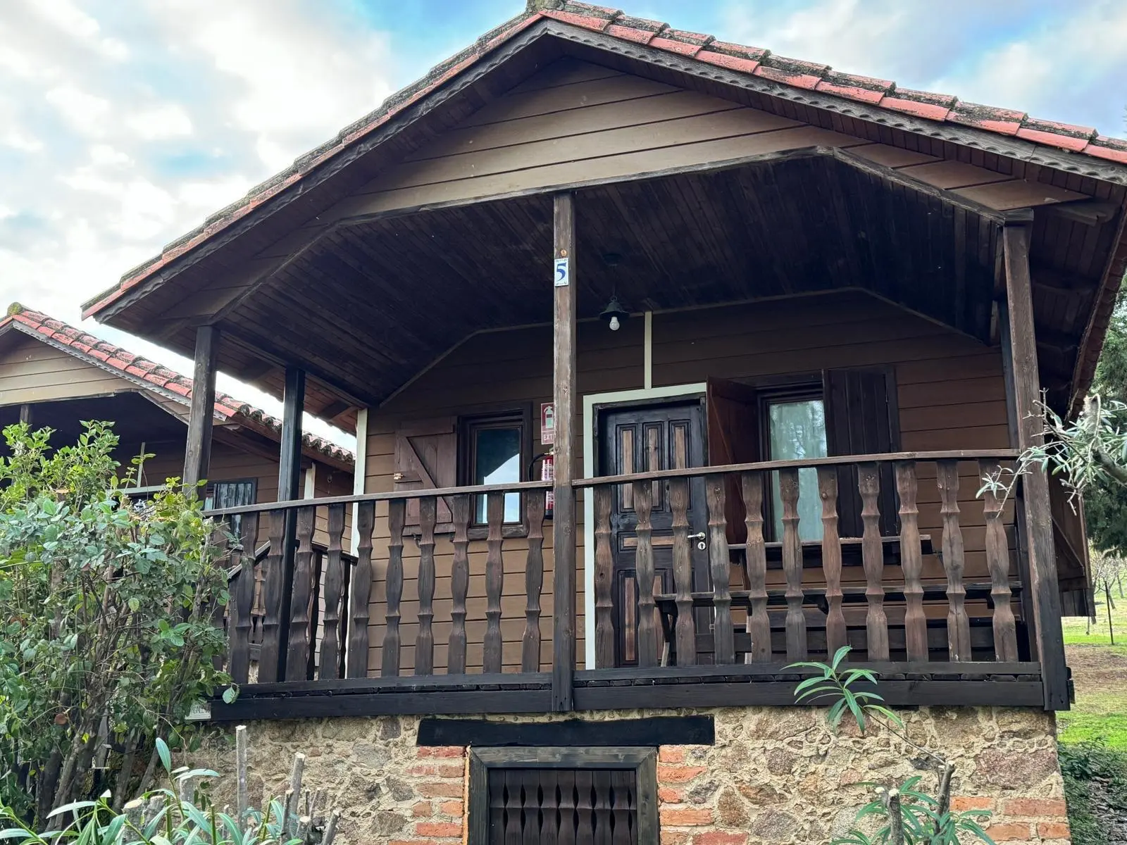 Bungalow con porche y barandilla de madera
