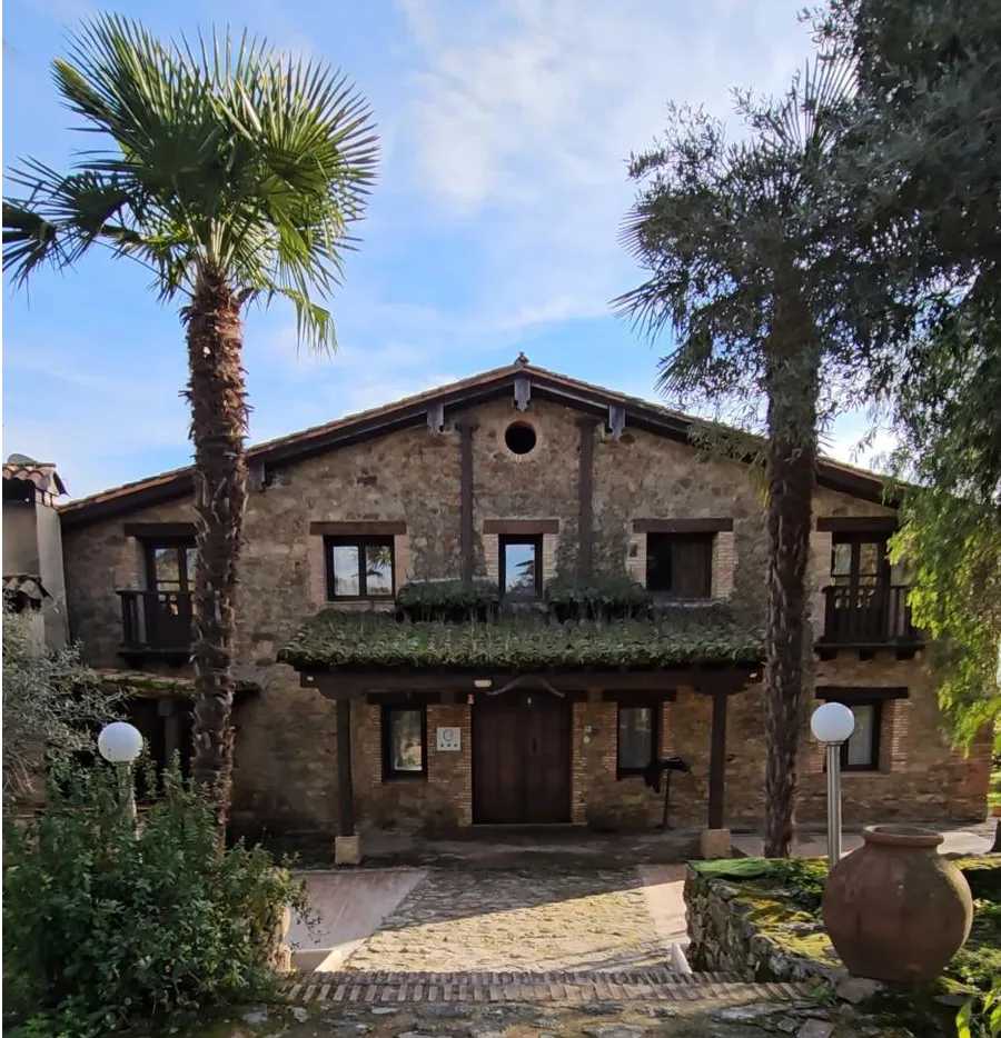 Fachada de piedra y madera de La Casona rodeada de palmeras