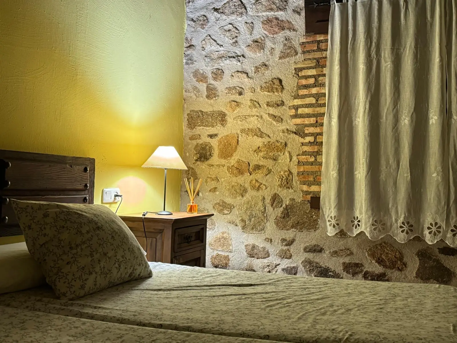 Habitación abuhardillada con pared de piedra en La Casona